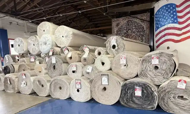 Rolls of carpet stacked under the painted flag in the All American showroom