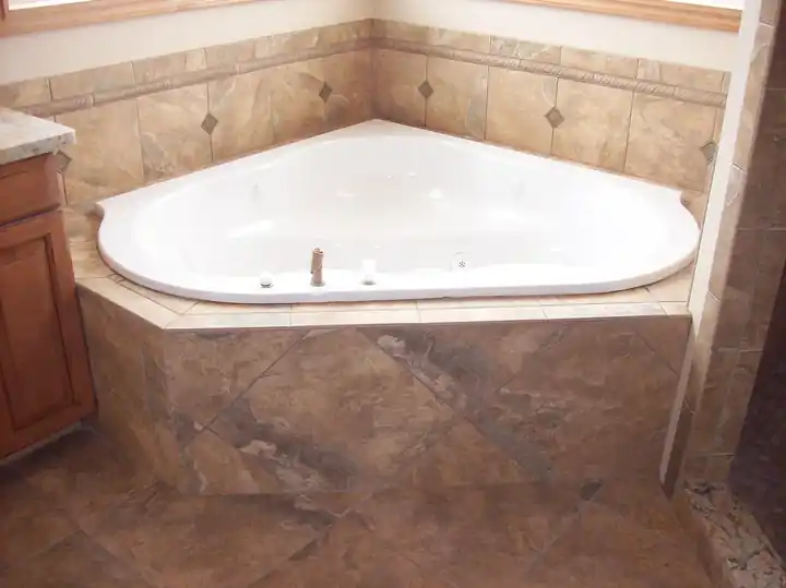 Corner soaking tub set into a tiled deck with a matching tile surround