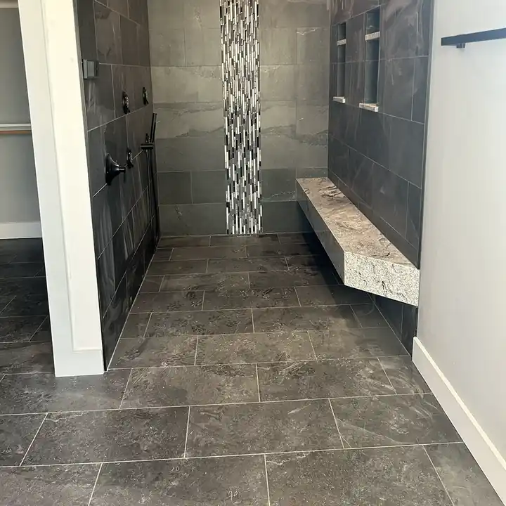 Curbless walk-in shower in large porcelain tile with a floating granite bench