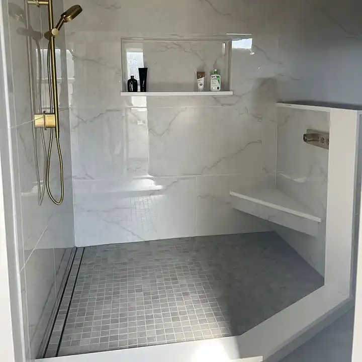 Walk-in shower with large marble-look porcelain tile and brass fixtures