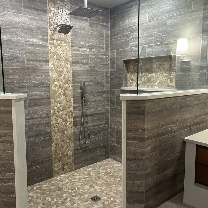 Shower with a natural pebble mosaic floor and an accent strip