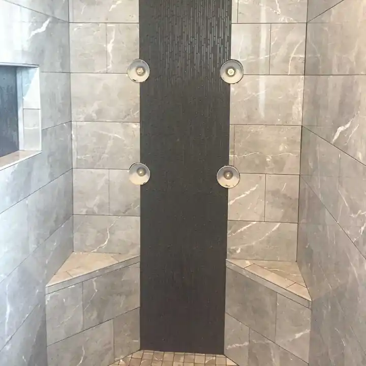 Porcelain tile shower with corner benches and a dark wet-look mosaic strip