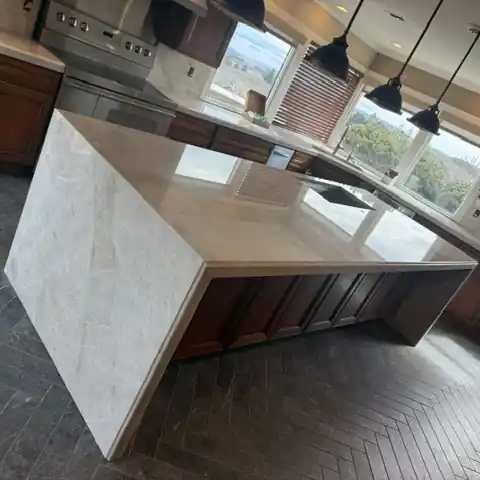 Finished kitchen with a Taj Mahal waterfall island, matching countertops and new backsplash
