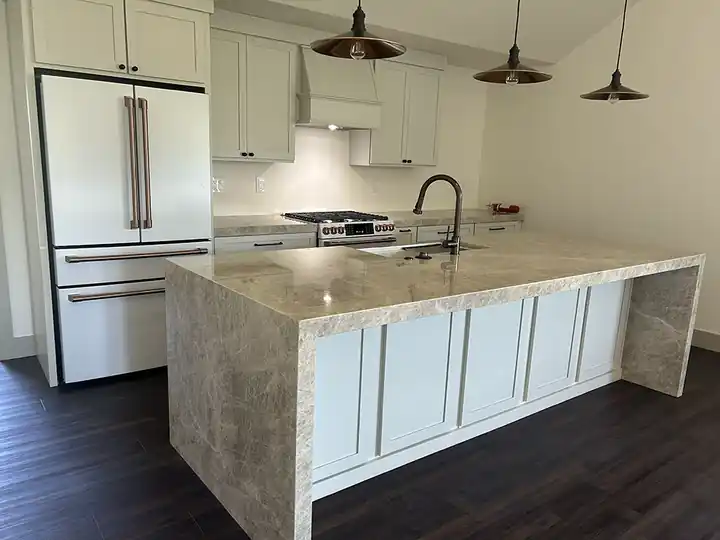 Bright kitchen with a white waterfall island and dark floor