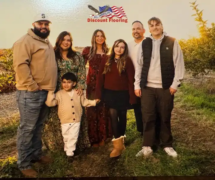 The Gutierrez family posed together beneath the All American Discount Flooring logo